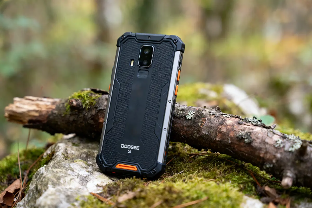 Smartphone robuste Doogee S sur un rocher mousseux en forêt, arrière-plan flou.