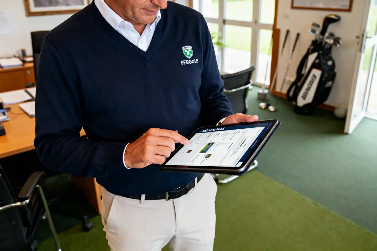 Homme consultent une tablette dans un bureau de golf, sac de clubs en arrière-plan.