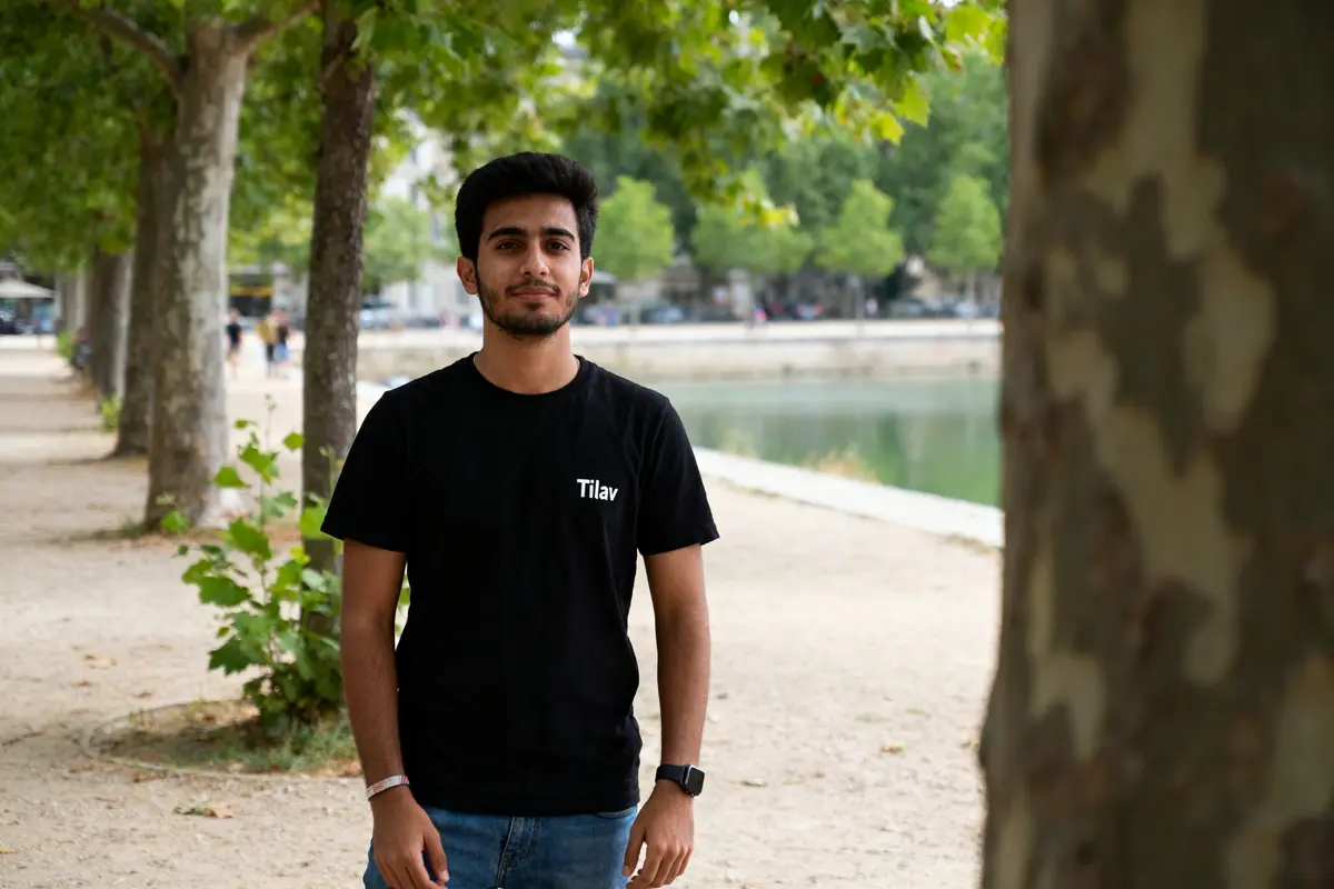Jeune homme en t-shirt tilav com noir marchant près d'un canal ombragé