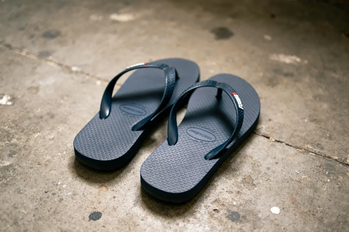 Paire de flip-flaps pour adulte bleus posés sur un sol en béton.